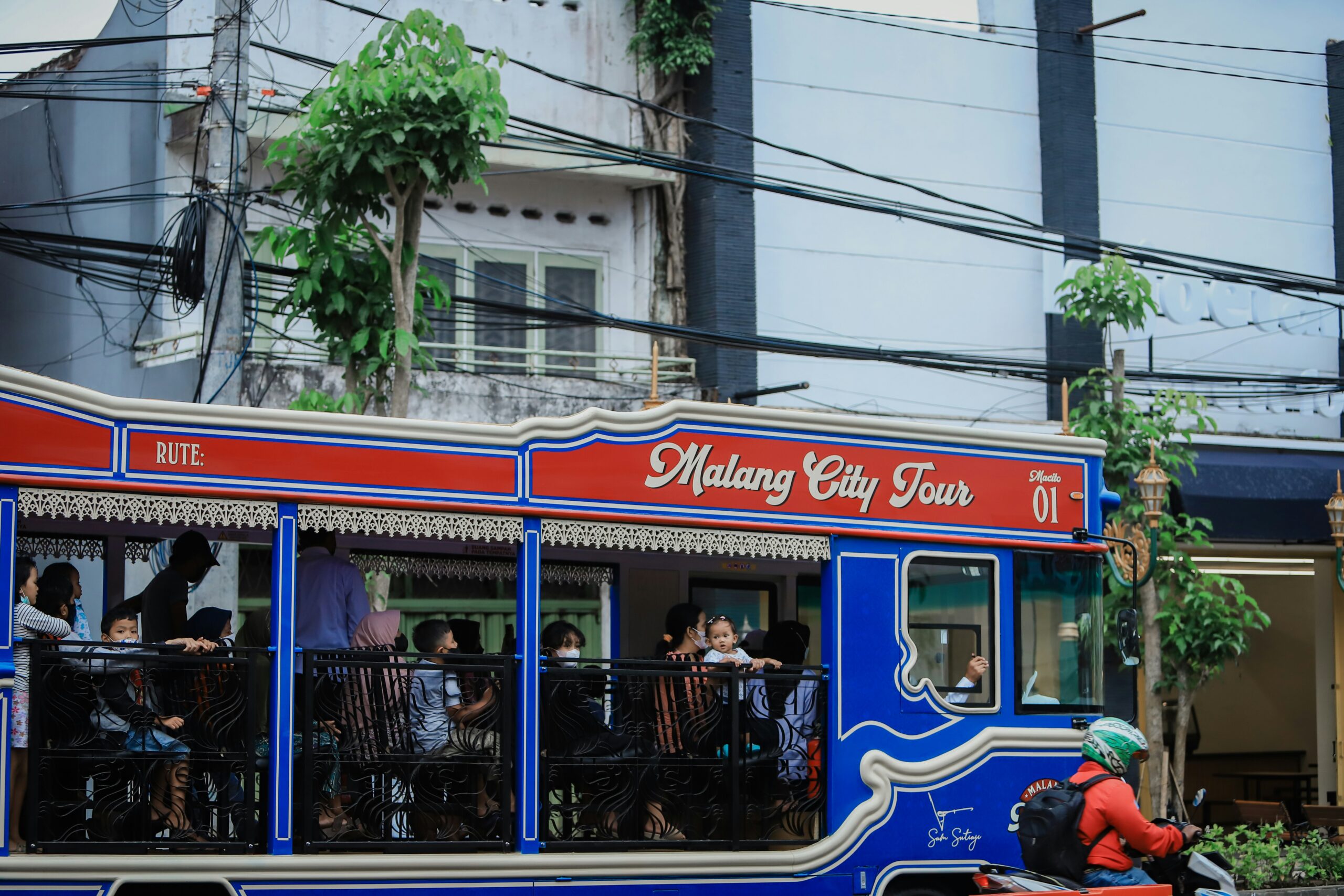 a blue and red trolley car with people on it